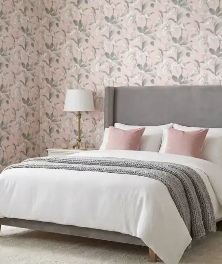 A romantic bedroom with soft pink floral wallpaper called Meridian Parade, with a grey velvet bed, and white bedding.